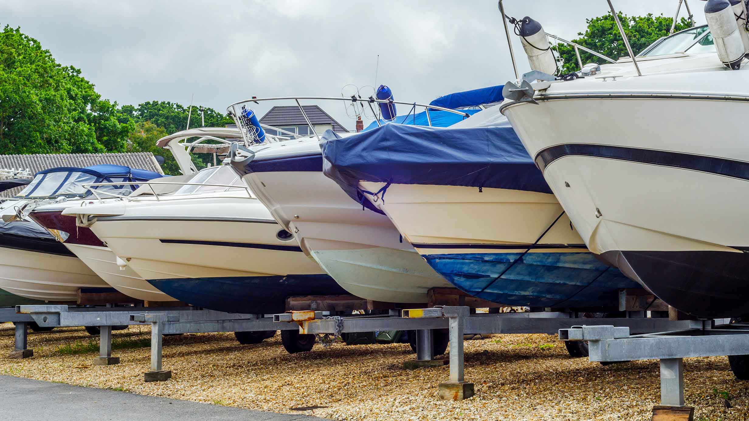 Six boats parked side by side, on boat trailers.